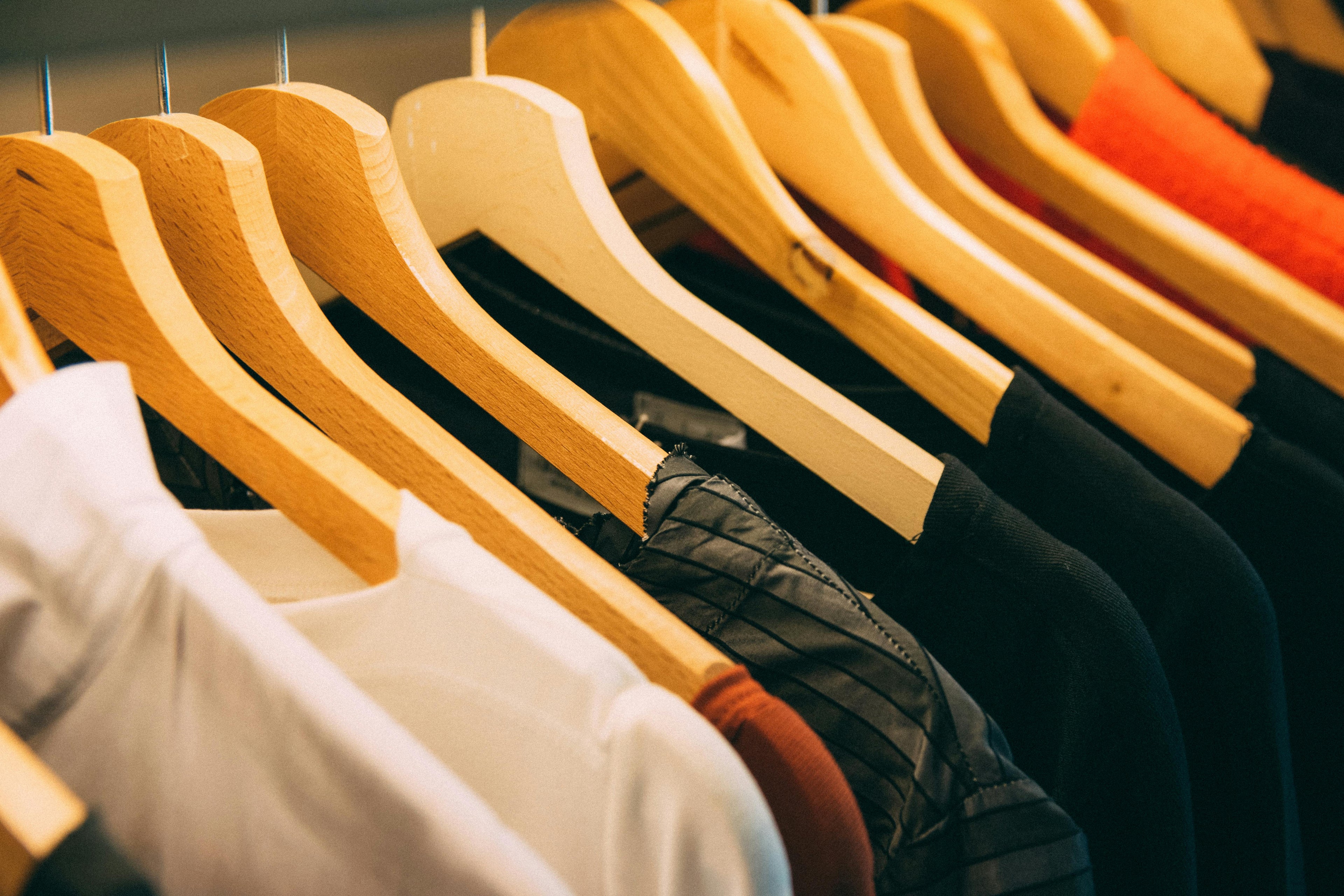 "Close-up of FLERO WEAR drop shoulder t-shirts in white, maroon, black, and striped designs on wooden hangers — premium oversized cotton streetwear for men and women in Pakistan"